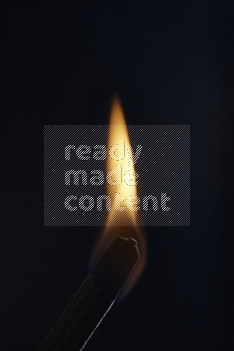 A burning incense stick isolated on dark backdrop