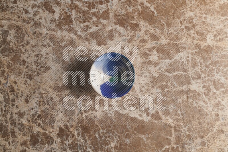 A multicolored pottery bowl on beige marble background