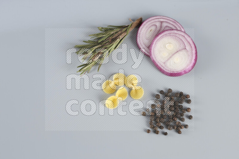 Raw pasta with different ingredients such as cherry tomatoes, garlic, onions, red chilis, black pepper, white pepper, bay laurel leaves, rosemary, cardamom and mushrooms on light blue background