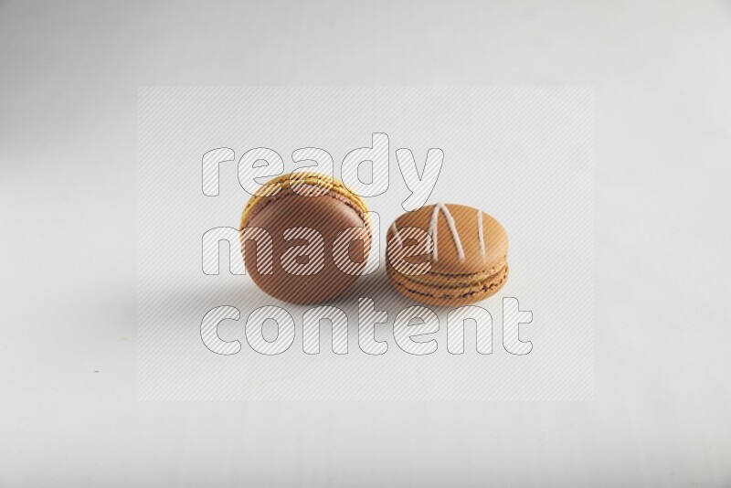 45º Shot of of two assorted Brown Irish Cream, and Yellow, and Brown Chai Latte macarons on white background