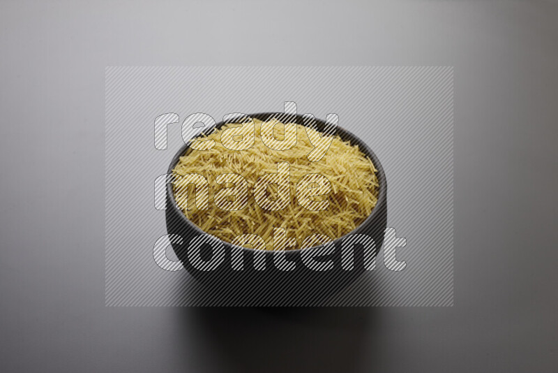 Vermicelli pasta in a pottery bowl on grey background