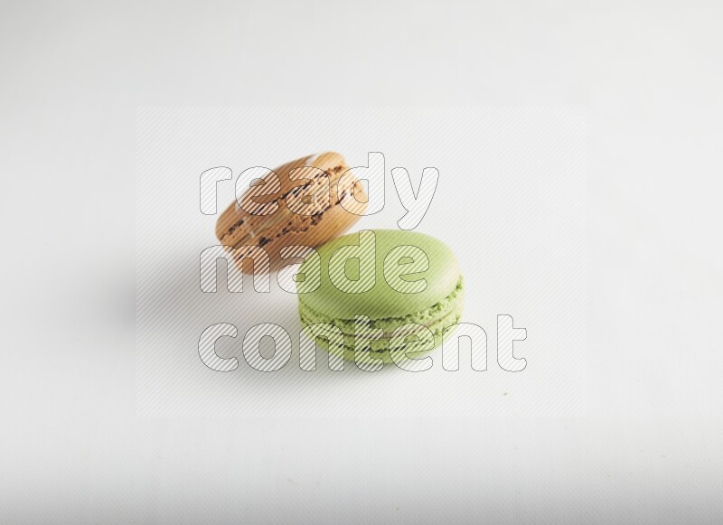 45º Shot of of two assorted Brown Irish Cream, and Green Pistachio macarons on white background