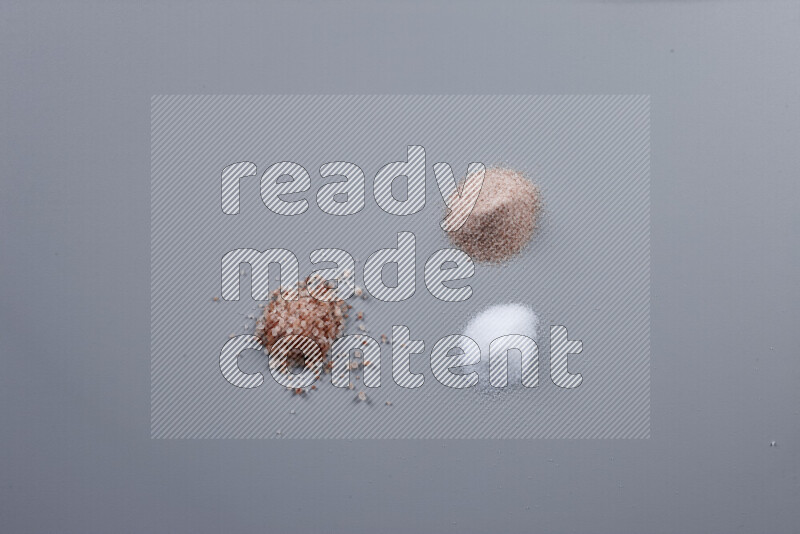 Bunches of table salt, coarse sea salt, fine himalayan salt and coarse himalayan salt on grey background