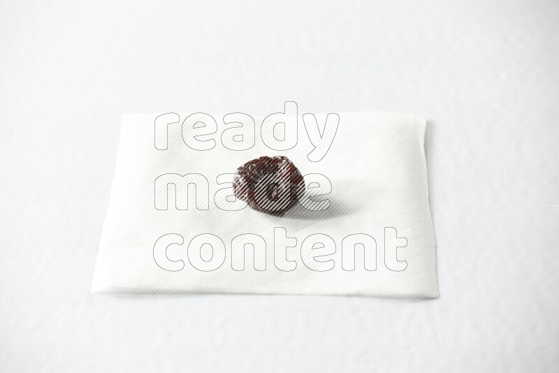 A dried plum on a piece of paper on a white background in different angles