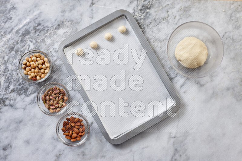 Ghoriba step by step with its ingredient, flour, powdered sugar, ghee and nuts on grey marble background