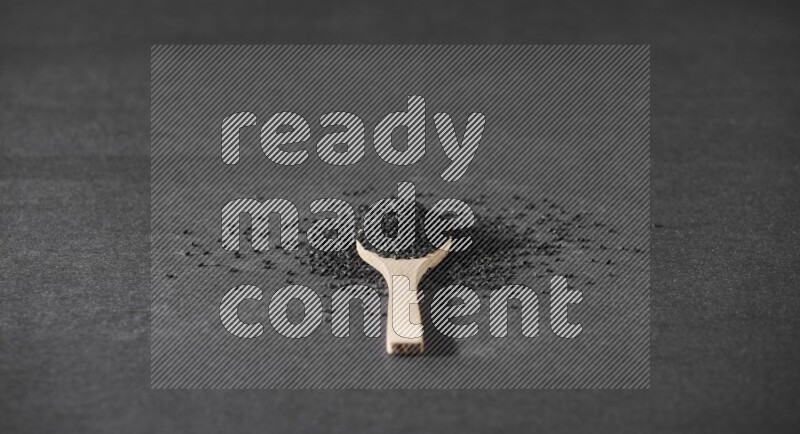 ملعقة خشبية ممتلئة بحبة البركة ومحاطه ببعض من الحبوب على أرضية سوداء