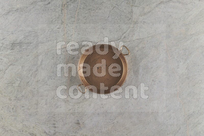A small copper pan on grey marble background
