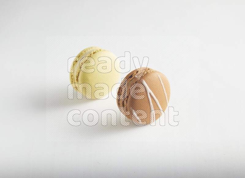 45º Shot of of two assorted Brown Irish Cream, and Yellow Lime macarons on white background