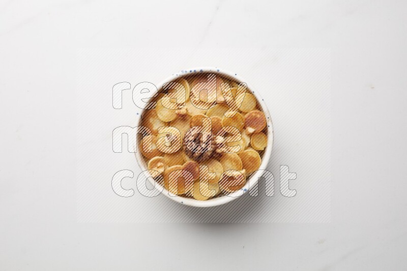 Top-view shot of walnut cereal pancakes in a round bowl on white background