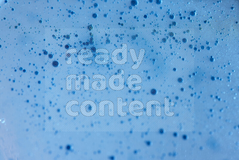 Close-ups of abstract blue watercolor drops on oil Surface on blue background