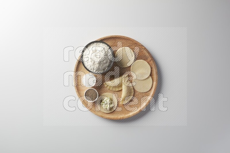 two closed sambosas and one open sambosa filled with cheese while flour, salt, and black pepper aside in a wooden dish on a white background