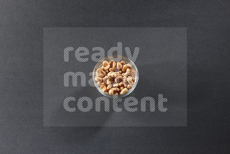 A glass bowl full of cashews on a black background in different angles