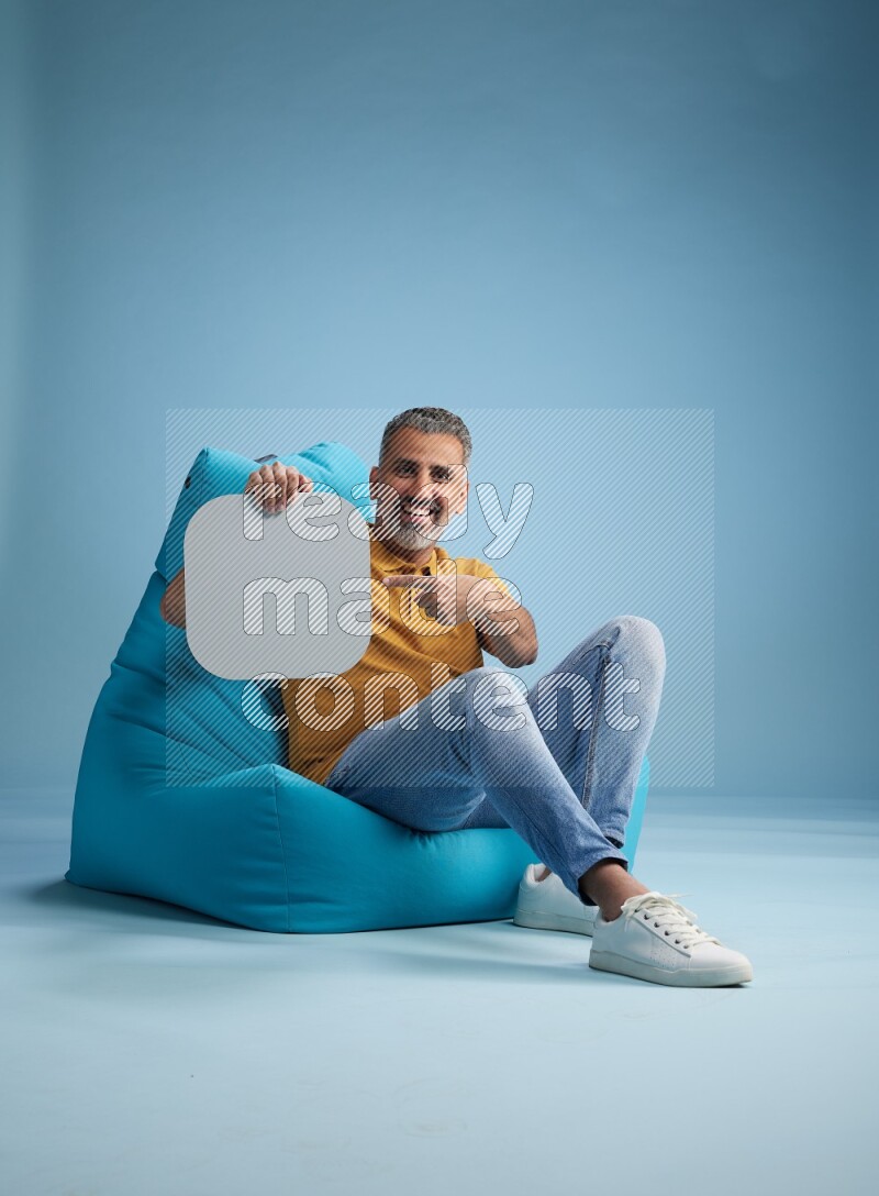 A man sitting on a blue beanbag and holding social media sign