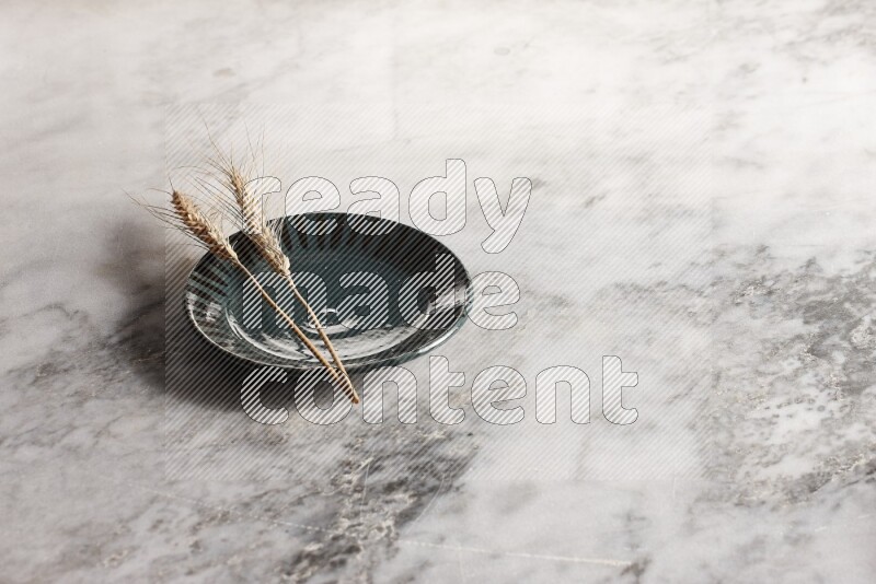 Wheat stalks on multicolored pottery plate on grey marble background