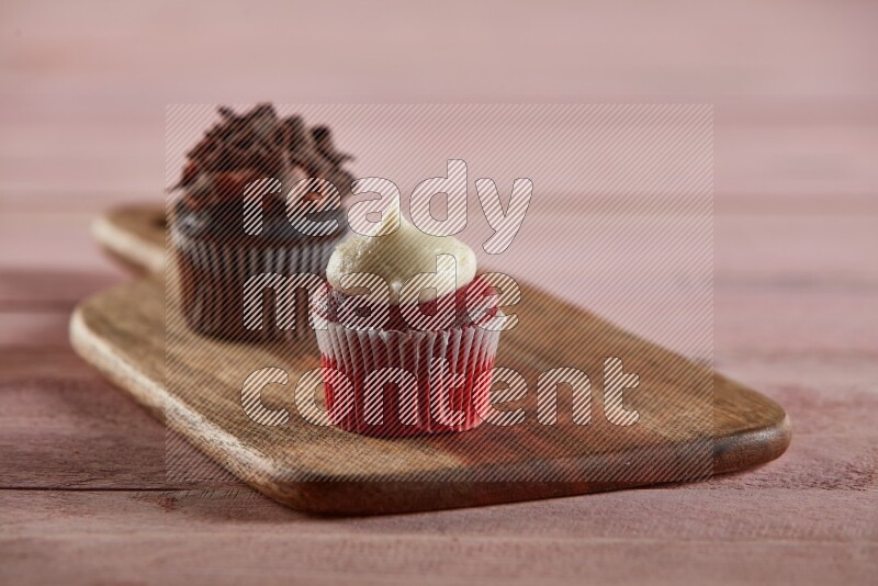 Red velvet mini cupcake topped with cream on a wooden board