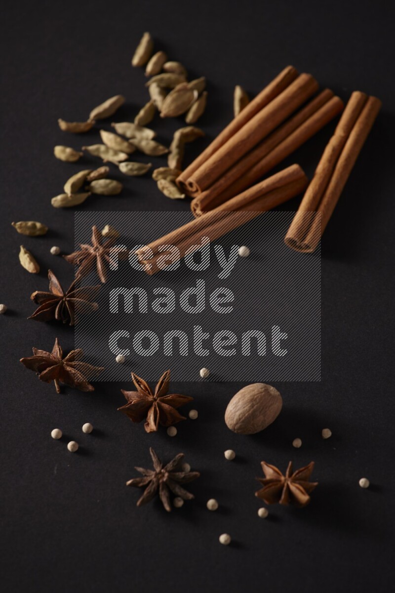 Cinnamon sticks, cardamom, star anise, nutmeg and white peppers on a black background