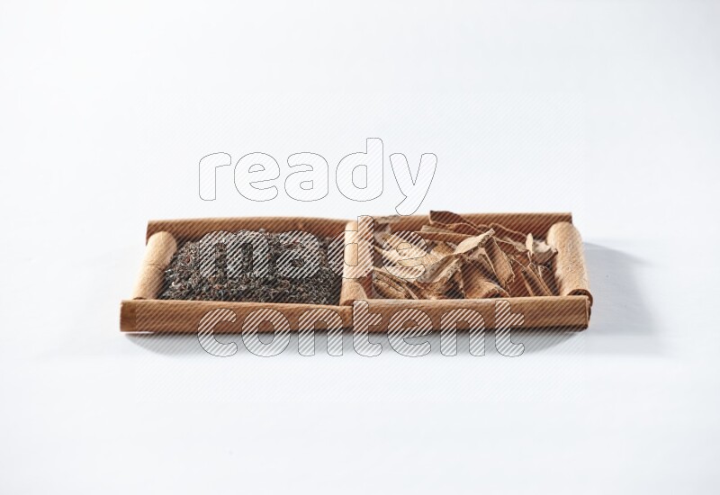 مربعان من أعواد القرفة ممتلئان بالشاي الأسود وقطع القرفة علي خلفية بيضاء