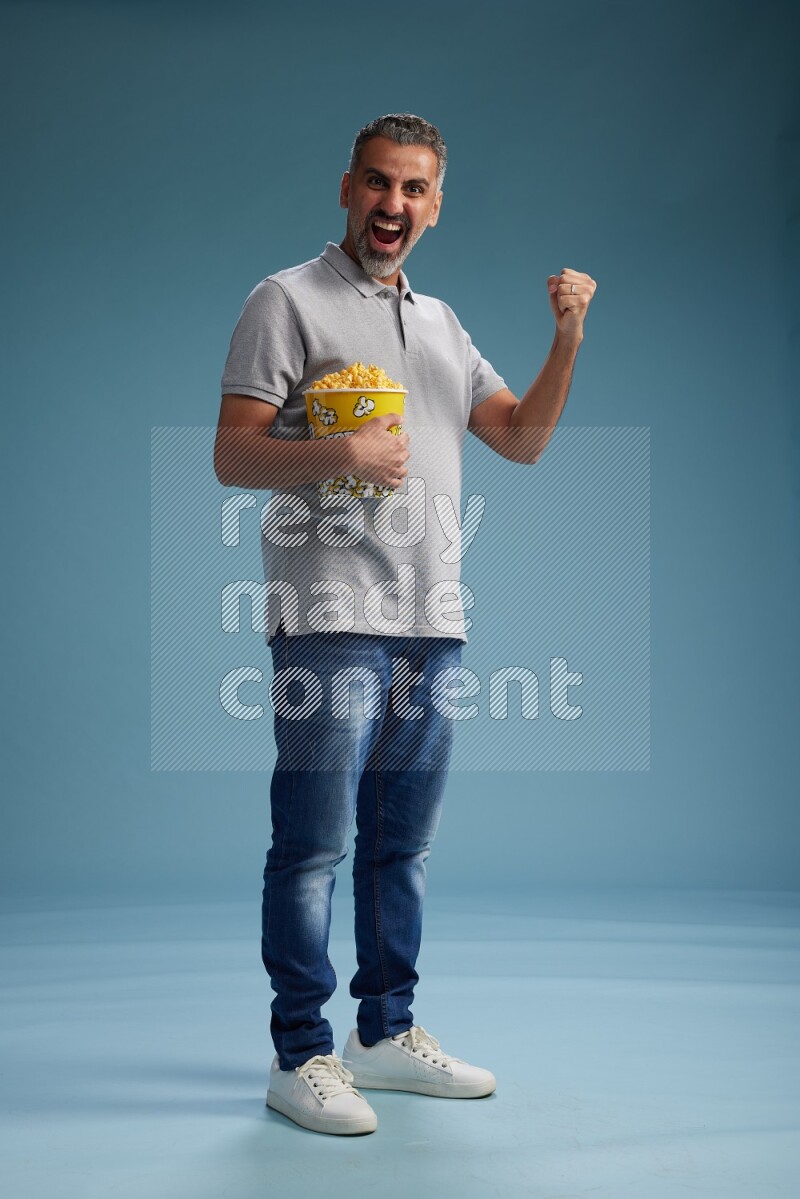 Man Standing eating popcorn on blue background
