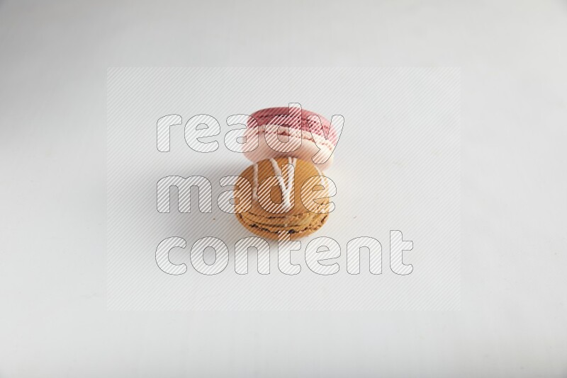 45º Shot of of two assorted Brown Irish Cream, and Pink Litchi Raspberry macarons on white background