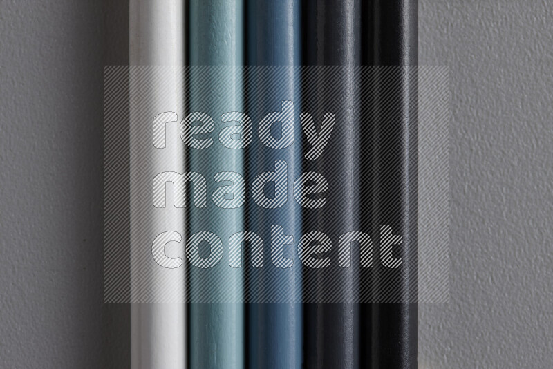 مجموعة من أقلام الرصاص الملونة مرتبة لتعرض تدرجا من اللون الأبيض والرمادي والأسود علي خلفية رمادية