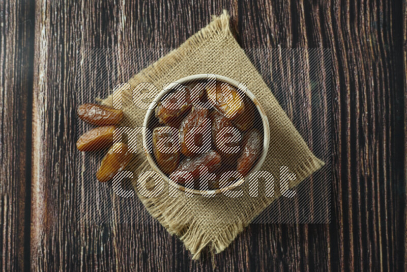 Dates in different bowls (wooden, pottery and glass) on wooden background