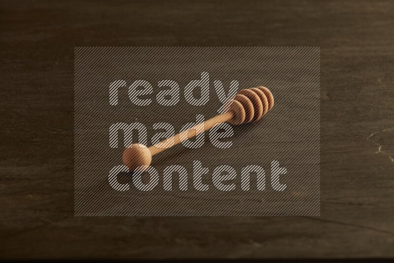 Wooden honey dipper on black slate background
