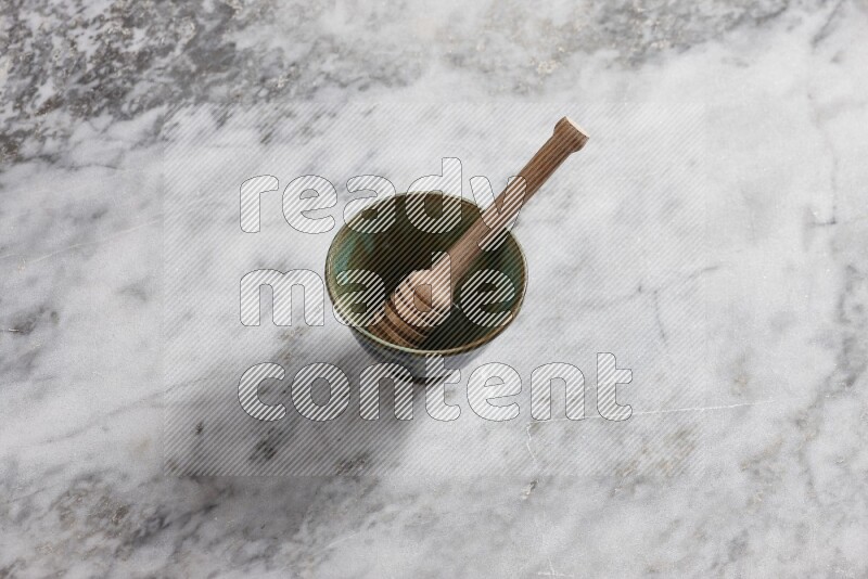 Decorative pottery bowl with wooden honey dipper in it on grey marble background