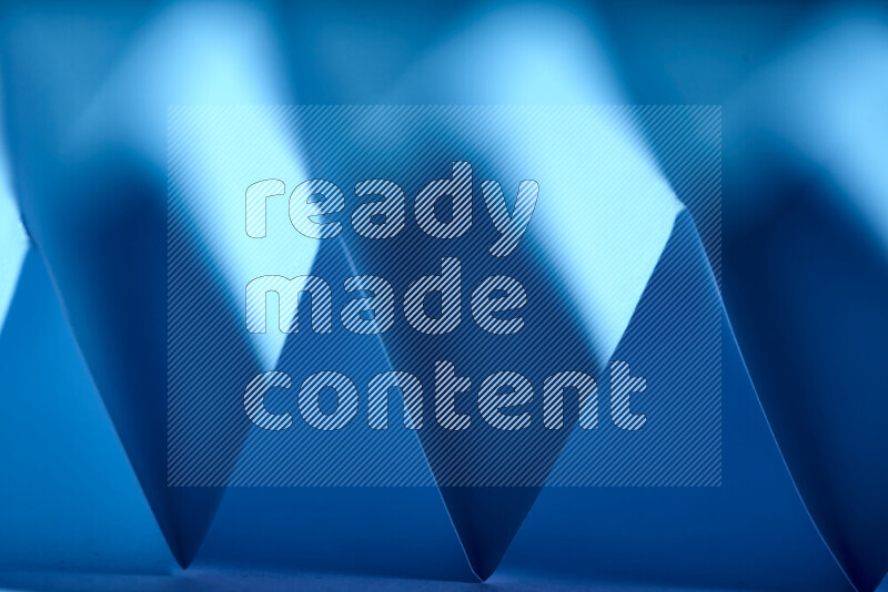 A close-up abstract image showing sharp geometric paper folds in blue gradients