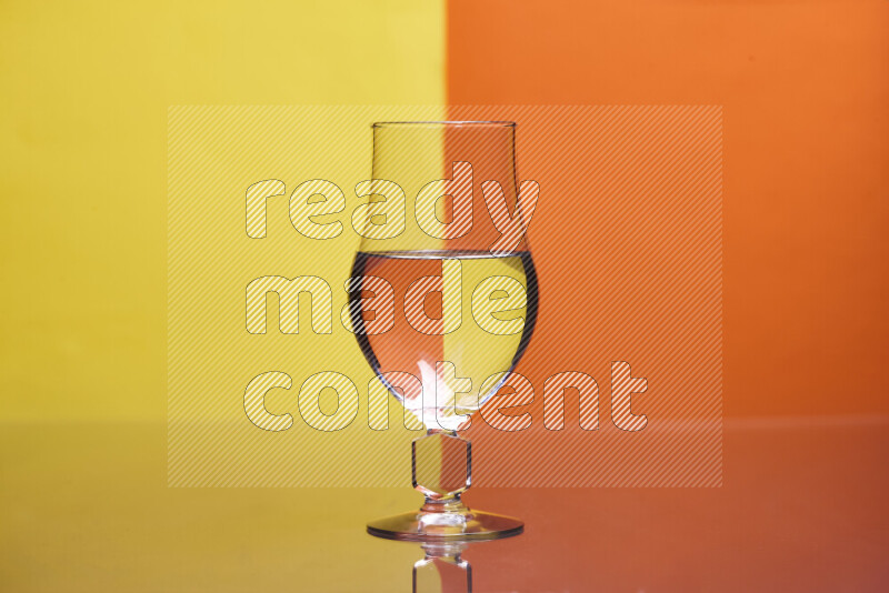 The image features a clear glassware filled with water, set against yellow and orange background