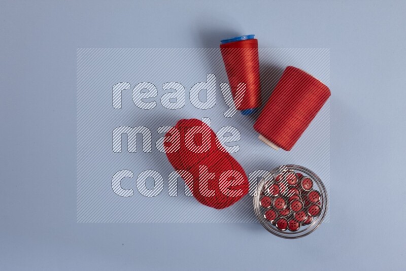 A red collection of sewing and tailoring tools arranged on a blue background
