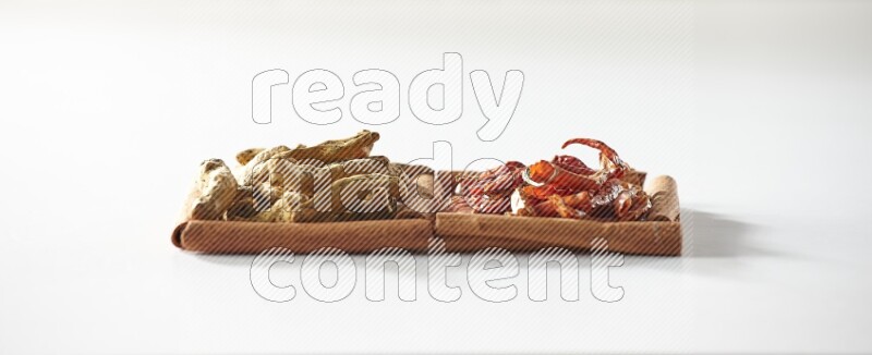 مربعان من أعواد القرفة ممتلئان بالفلفل الحار المجفف وأصابع الكركم علي خلفية بيضاء