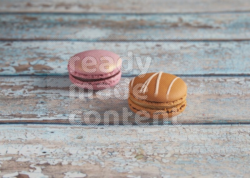 45º Shot of of two assorted Brown Irish Cream, and Purple Strawberry macarons  on light blue background