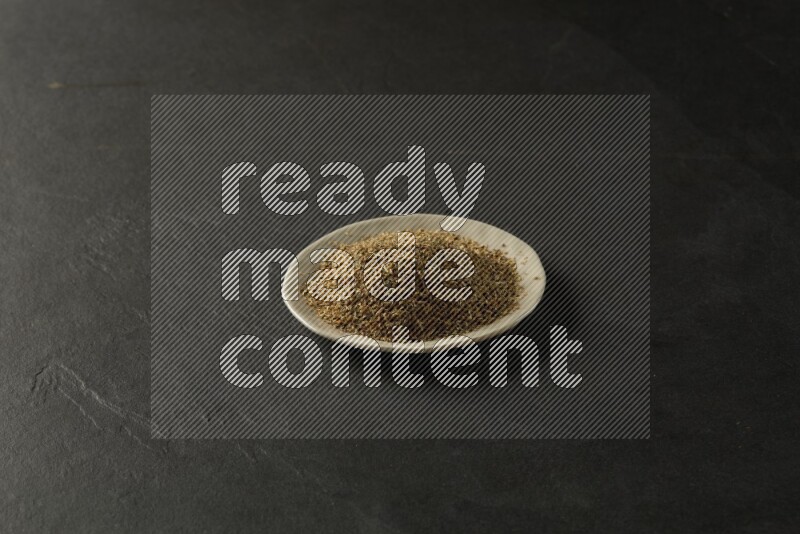 white ceramic round sauce dish filled with herbs on grey textured countertop