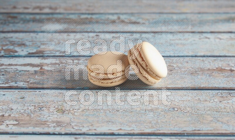 45º Shot of two White Caramel fleur de sel macarons on a light blue wooden background