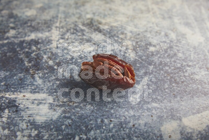 pecan stuffed madjoul date on a rustic blue background