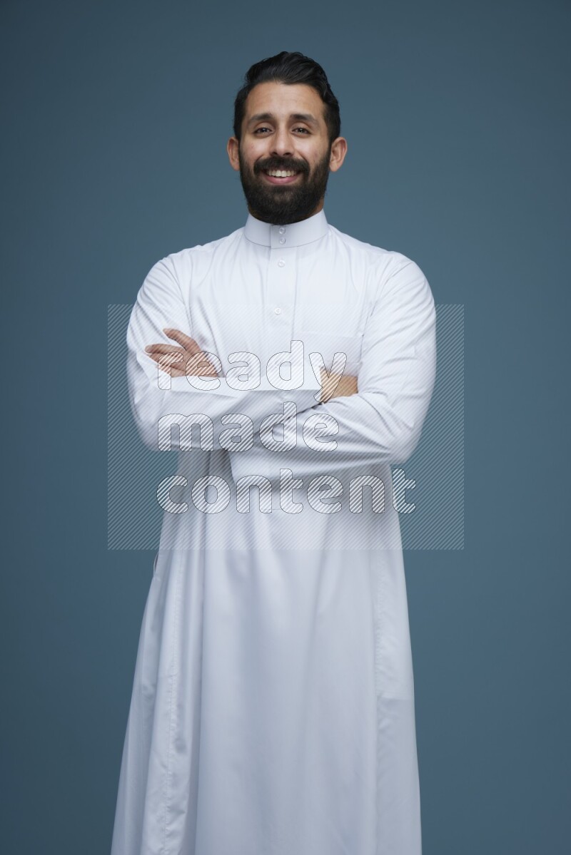 A man posing in a blue background wearing Saudi Thob