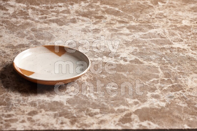 A multicolored pottery plate on beige marble background