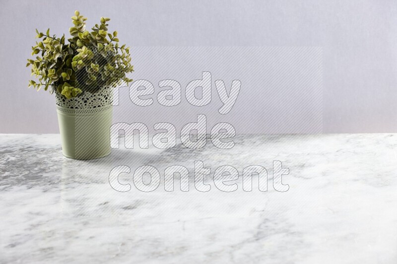 Artificial plant in green decorative pot on grey marble background