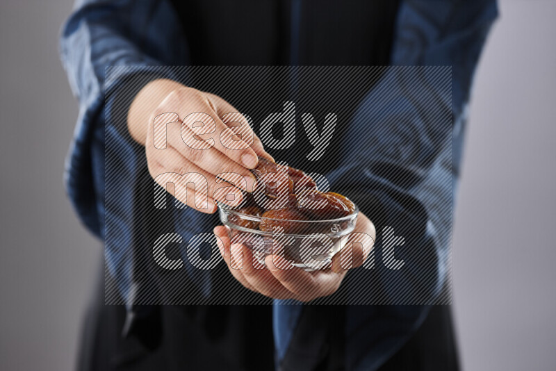 امرأة ترتدي عباءة تحمل أنواع مختلفة من التمر في أوضاع متعددة