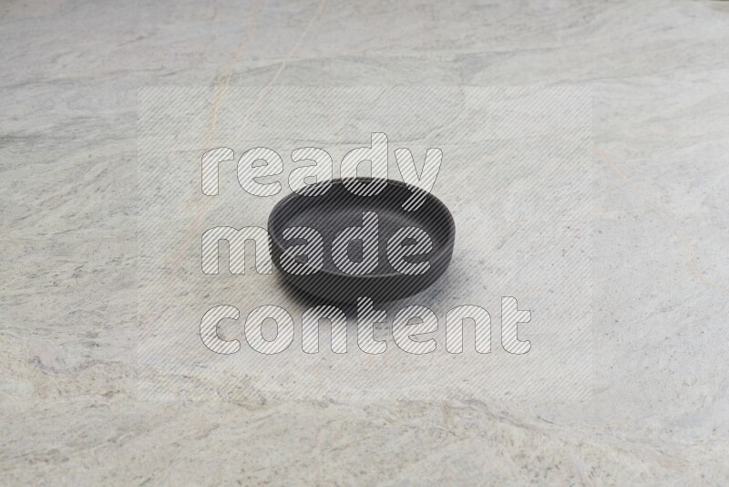 A black pottery oven bowl on grey marble background