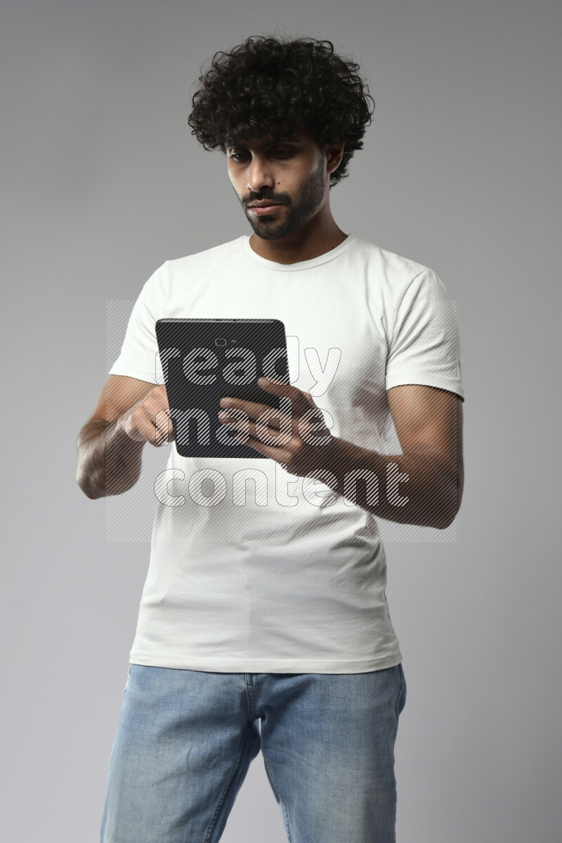 A man wearing casual standing and browsing on a tablet on white background