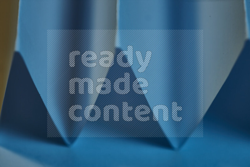A close-up abstract image showing sharp geometric paper folds in blue gradients