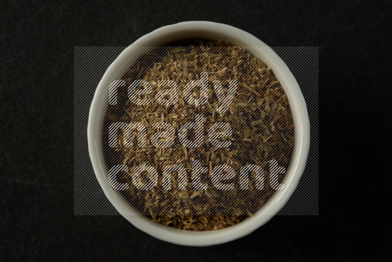 white ceramic round sauce bowl filled with herbs on grey textured countertop