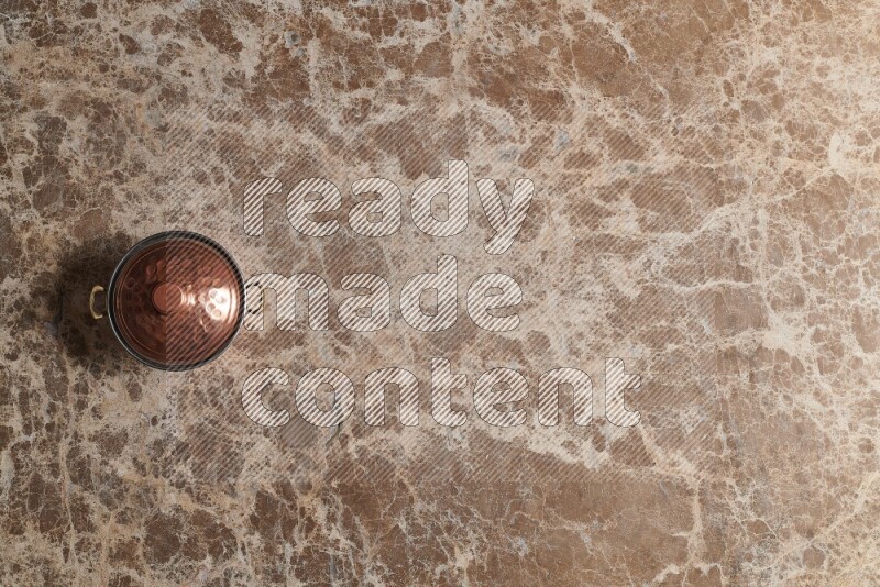 A small copper pot on beige marble background