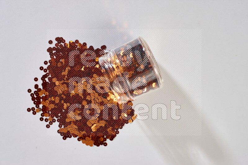 Colored flat sequins in a glass jar on grey background