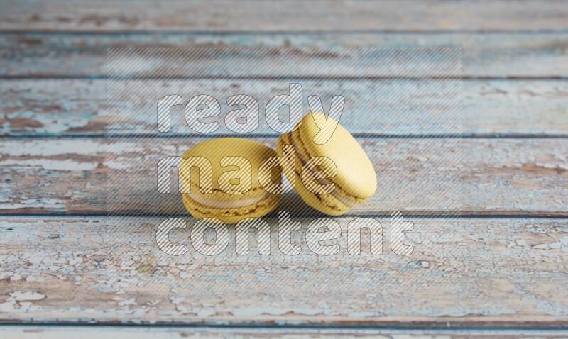 45º Shot of two Yellow Lime macarons on light blue wooden background
