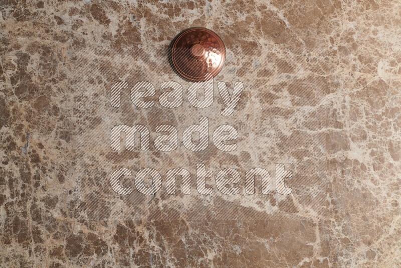 A small copper pot on beige marble background