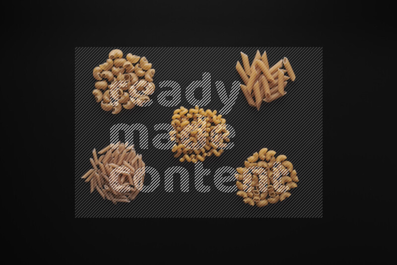 Different pasta types in bunches on black background