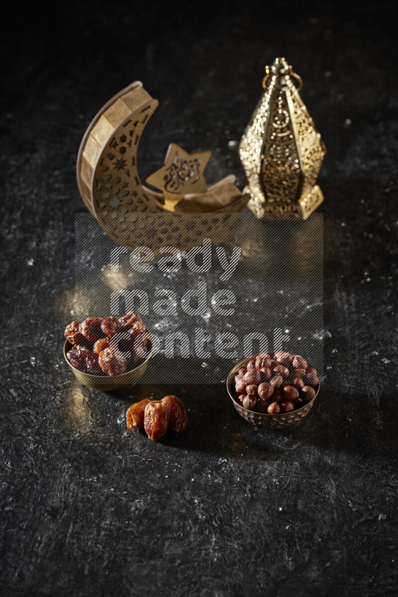 Dates in a metal bowl with hazelnuts beside golden lanterns in a dark setup