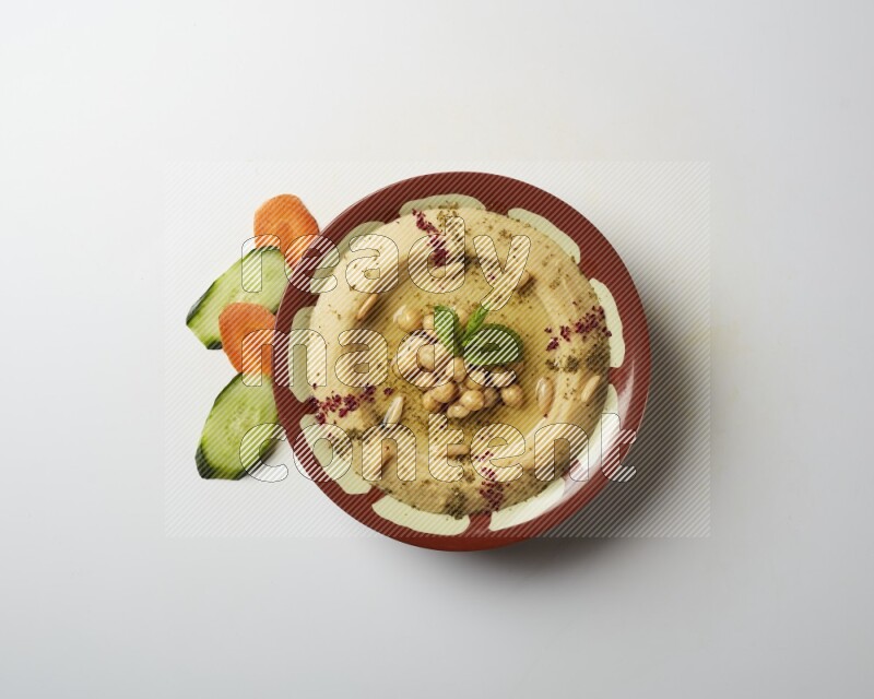 Hummus in a traditional plate garnished with zaatar & sumak on a white background